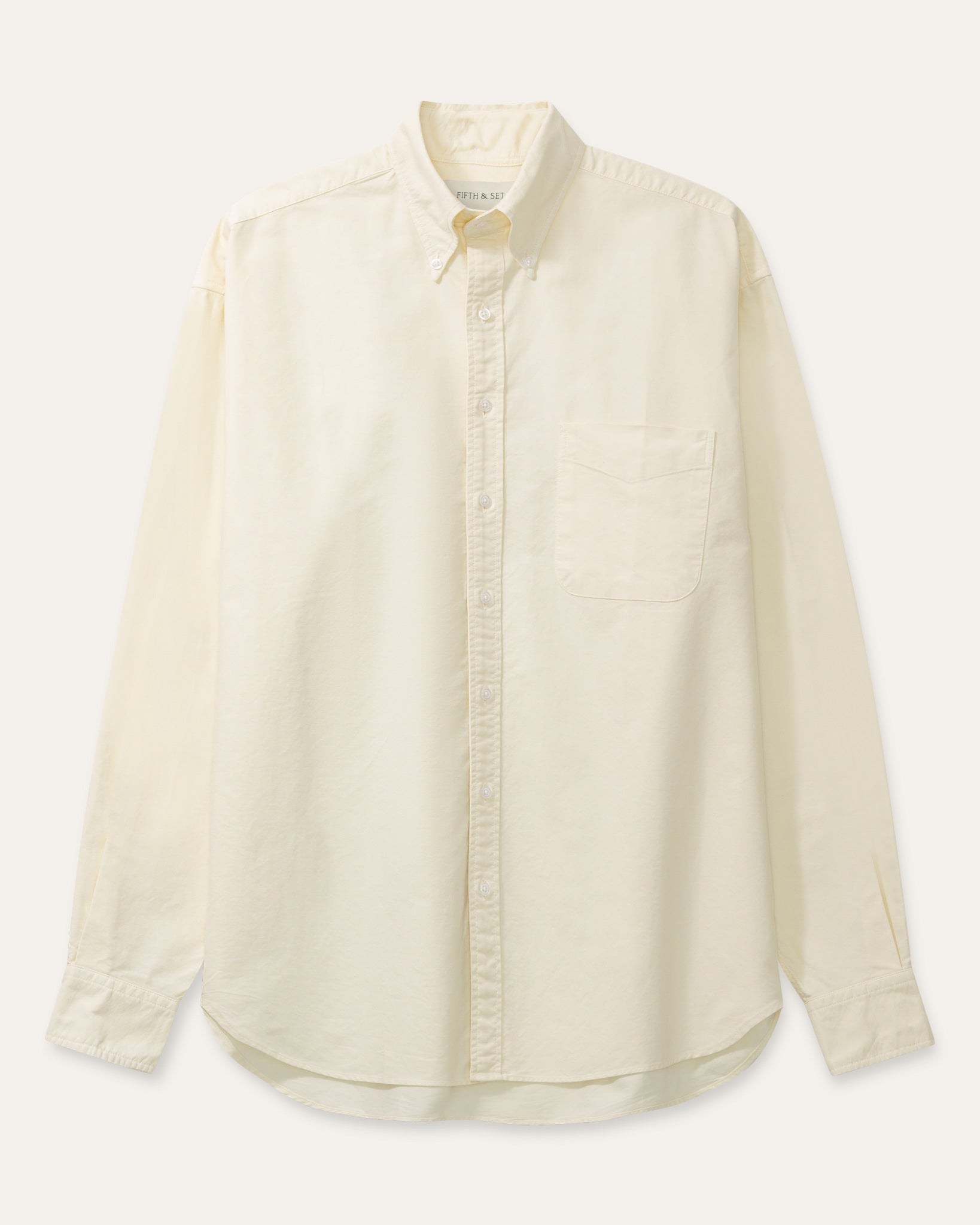 A cream long-sleeve button-down shirt with a single chest pocket, laid flat against a light beige background.