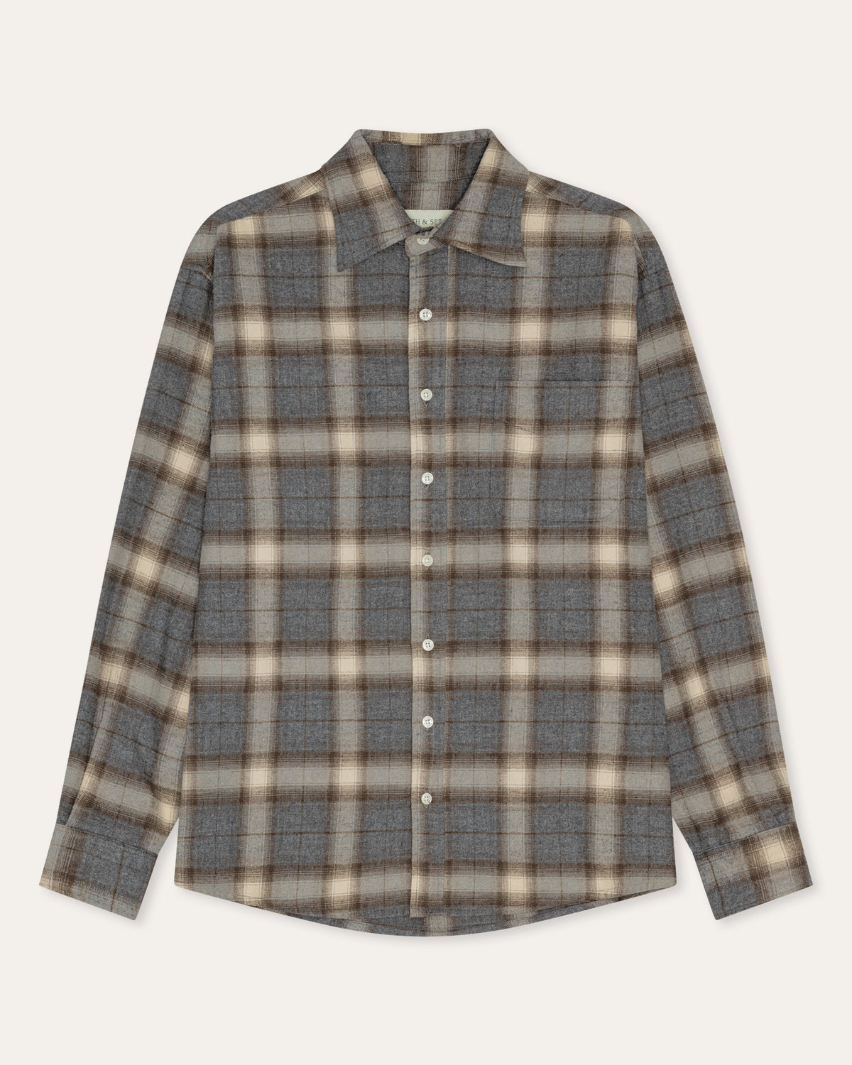 A long-sleeve button-up plaid shirt in gray, beige, and brown tones, laid flat against a light cream background.