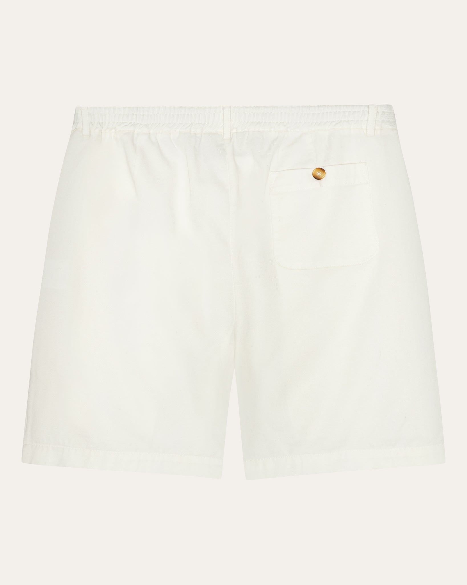 A pair of pleated tennis shorts in warm white color with a relaxed fit, partially elasticated waistband, and extra large front pockets.
