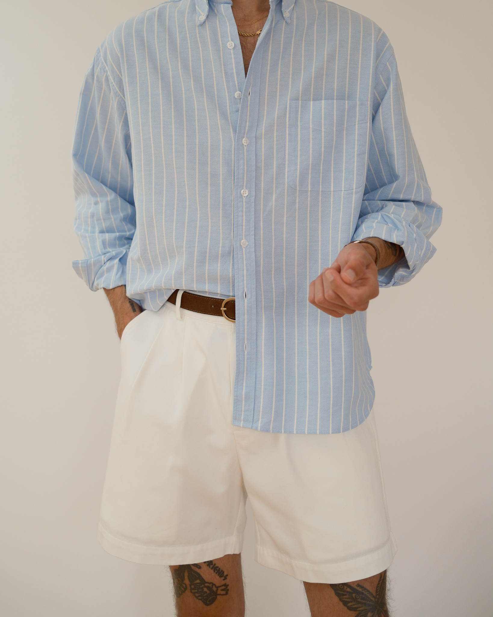 model standing in front of white wall wearing white shorts and a blue and white striped shirt
