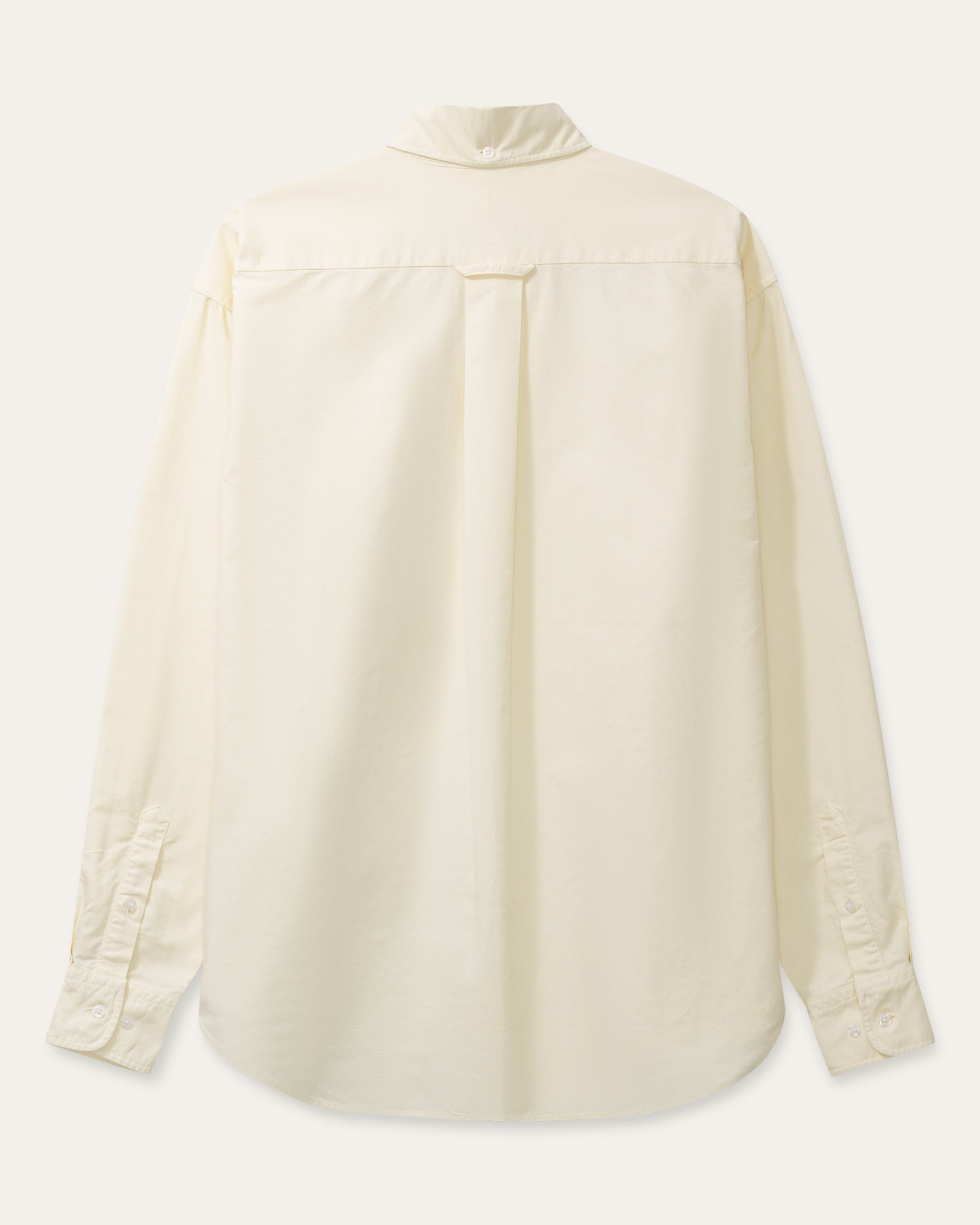 A cream long-sleeve button-down shirt with a single chest pocket, laid flat against a light beige background.