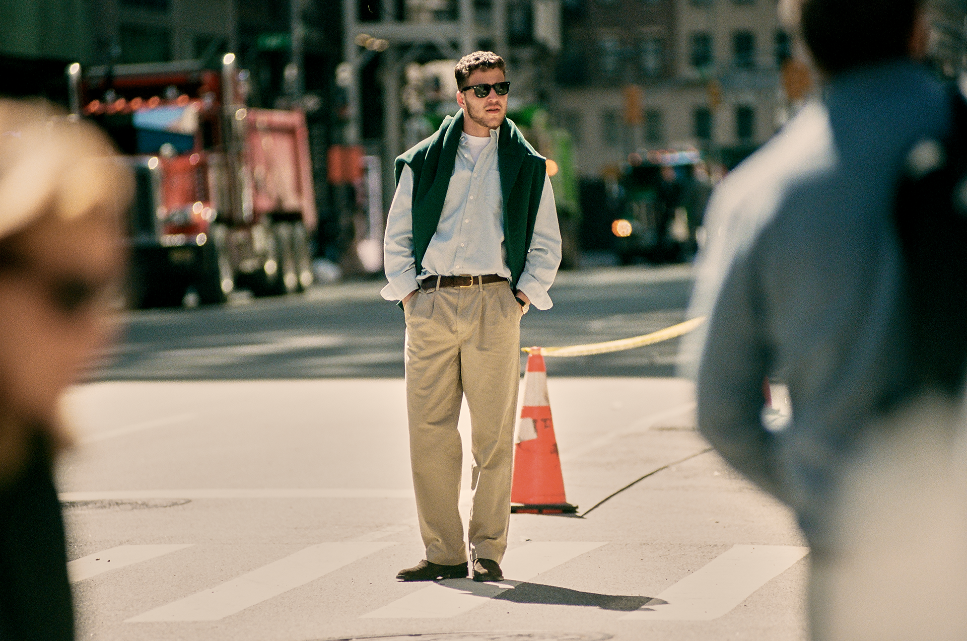 Man standing on a city street with traffic cones and vehicles in the background